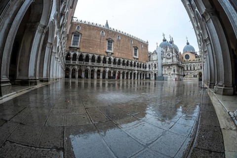 The doge's palace courtyard glistens with rainwater on a cloudy day in venice, italy, showcasing