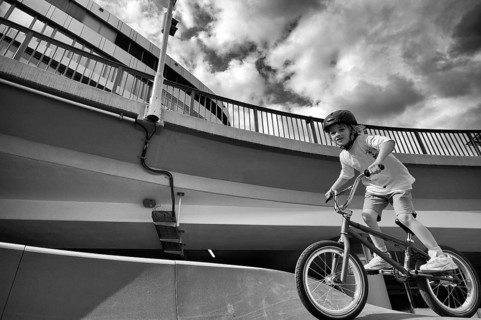 Boy, blonde, 6 years, riding bicycle, bike, crash helmet, subway, urban, concrete, black and white,