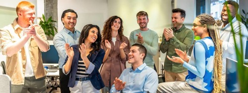 Happy colleagues clapping, celebrating a successful project or good news in a modern office