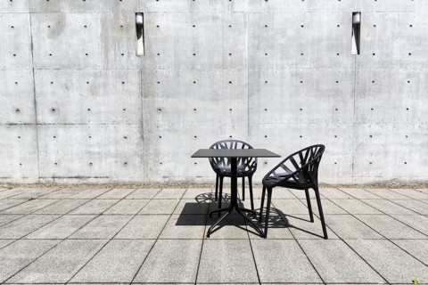 Black table and two plastic chairs in the courtyard made of exposed concrete, architect Tadao Ando,