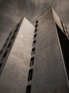 A striking building features unique geometric shapes and intricate brickwork, towering high against