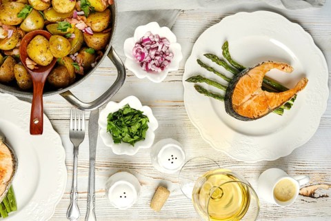 A beautifully arranged meal featuring a salmon fillet on asparagus, accompanied by seasoned