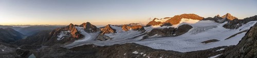 Picturesque high mountain landscape at sunrise with alpenglow, glacier and rocky mountain peaks in