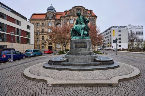 Monument to Otto von Guericke, pavement made of cobblestones, lantern, parking lane with vehicles,