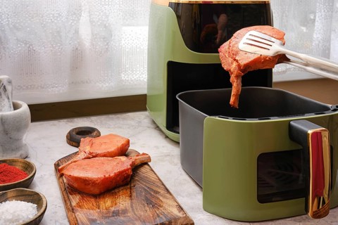 Thick pork rib chops are being cooked in an air fryer, showcasing the ease of preparing tender meat