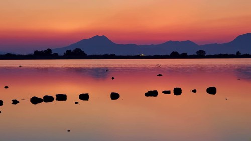 Dusk at the lake with dramatic sky and mountain silhouettes, salt lake, Tigaki, nature reserve,