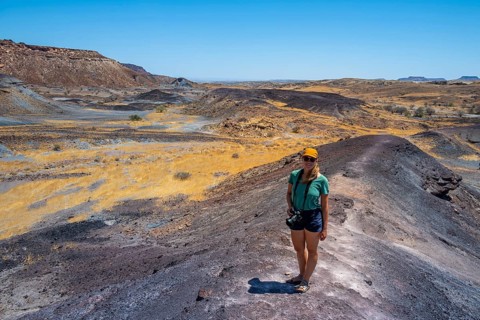 Tourist, Dry landscape with yellow grass and black volcanic hills, Burnt Mountain, Damaraland,