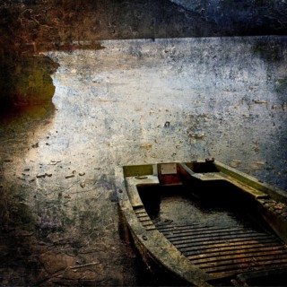 A weathered boat lies still on a serene water body at dusk, with reflections of light dancing on