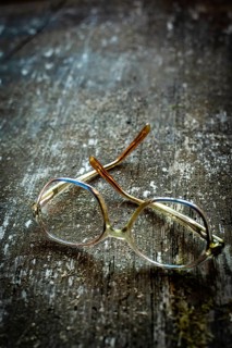 Unique vintage eyeglasses with a simple design rest on a weathered wooden surface, basking in warm