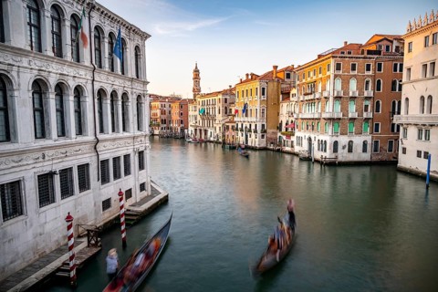 View of the Grand Canal with gondoliers at sunset, picturesque evening mood with palazzos on the