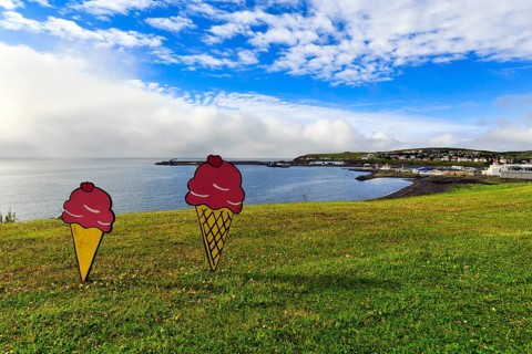 Two ice-cream cones in summer, signs in a meadow by the sea, fun decoration on Candy Day, Cumulus,