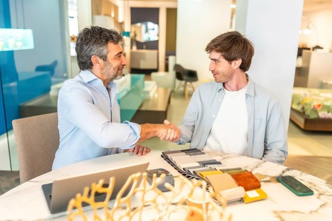 Interior designer shaking hands with a client in a furniture store showroom after choosing