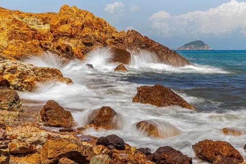 Rugged rocks and foaming spray on Topinetti beach, near Rio Marina, Elba Island, Tuscan Archipelago