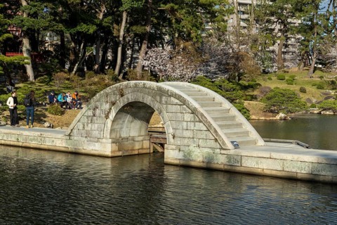 Shukkei-en with Koko-kyo stone bridge over Takuei-chi pond in spring, historical Japanese strolling