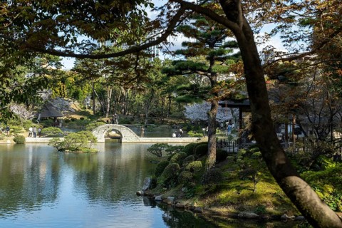 Shukkei-en with Koko-kyo stone bridge over Takuei-chi pond in spring, historical Japanese strolling