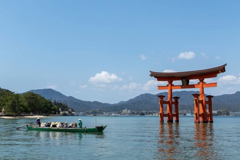 An excursion boat with tourists passes through the torii in the water, sight, tourist attraction,