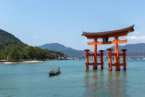 An excursion boat with tourists passes through the torii in the water, sight, tourist attraction,