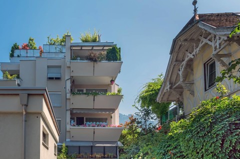 Grey façade, green flat roof and concrete balconies with floral decorations and old villa,