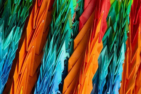 Chains of colourful origami cranes made of paper as a sign of peace in the Peace Park, close-up,