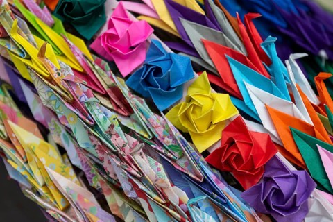 Chains of colourful origami cranes made of paper as a sign of peace in the Peace Park, close-up,