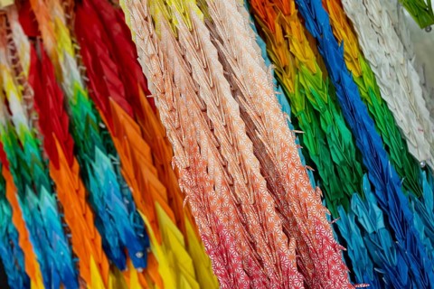 Chains of colourful origami cranes made of paper as a sign of peace in the Peace Park, close-up,