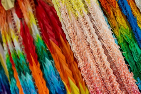 Chains of colourful origami cranes made of paper as a sign of peace in the Peace Park, close-up,