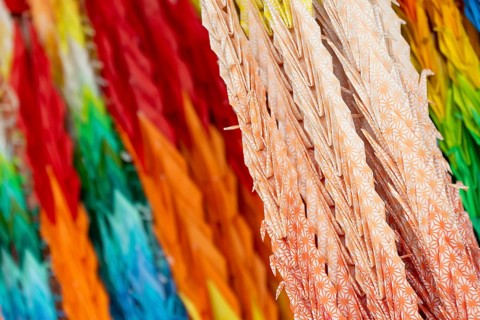 Chains of colourful origami cranes made of paper as a sign of peace in the Peace Park, close-up,
