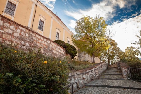 An idyllic path with stone steps and autumn trees leads to a yellow building, Mikulov Nikolsburg