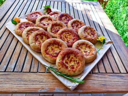 Several small pizzas on a wooden board decorated with flowers, presented on a garden table, Lower