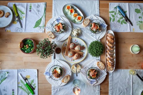 A stylishly laid table with a selection of fresh dishes, decorated with herbs and candlelight,