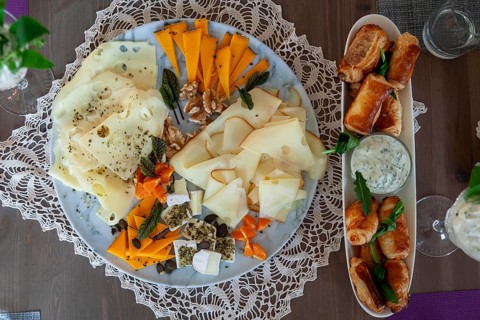 A cheese platter with different types of cheese and dumplings, decorated with herbs on a wooden