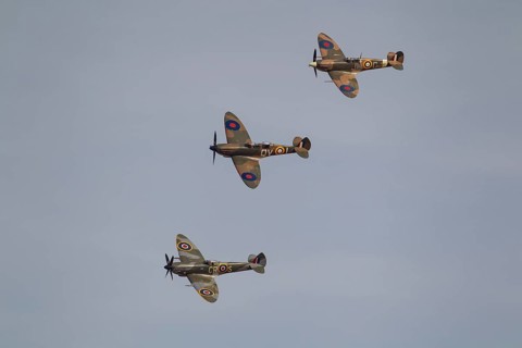 Supermarine Spitfire three warbird military aircraft in Royal air force RAF colours flying,