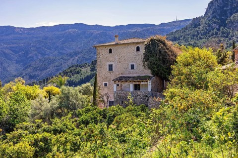 Old stone house in an fruit orchard with lush foliage in a mountainous area, Mallorca, Spain