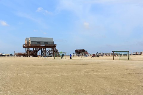 Pile dwellings, toilet block on the beach, beach chairs, football goal on the horizon, Sankt