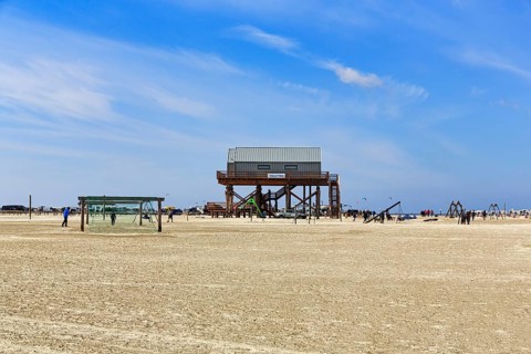 Pile dwelling, toilet block on the beach, football goal, walkers on the horizon, Sankt