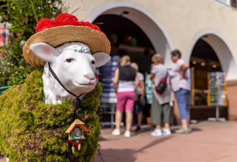 Kitsch in Black Forest style. A sheep with a Bollenhut and cuckoo clock. Freudenstadt,