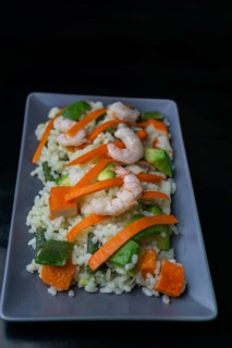 Rice salad with shrimp, red bell pepper and avocado, on black background