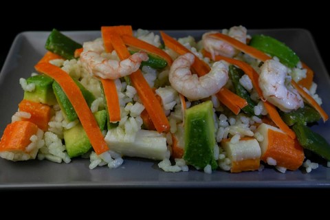 Rice salad with shrimp, red bell pepper and avocado, on black background