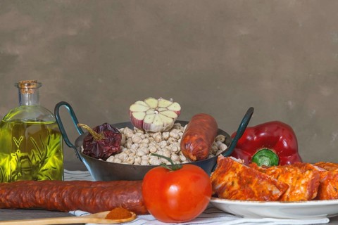 Raw chickpeas in a casserole with the ingredients to make the stew