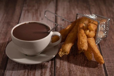 Cup of hot chocolate with freshly made churros on wooden background typical spanish breakfast on