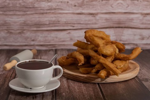 Cup of hot chocolate with freshly made churros on wooden background typical spanish breakfast on