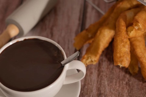 Cup of hot chocolate with freshly made churros on wooden background typical spanish breakfast on