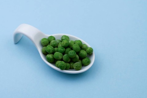White ceramic spoon with peas and blue bottom