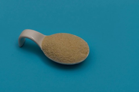 White ceramic spoon with breadcrumbs and blue background