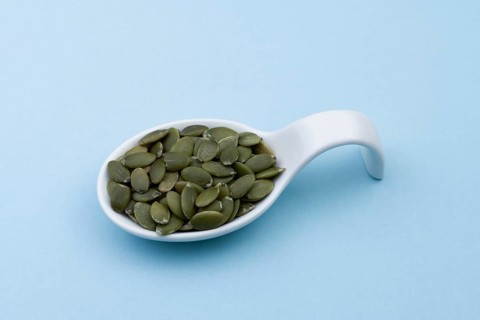 White ceramic spoon with pumpkin seeds and blue bottom