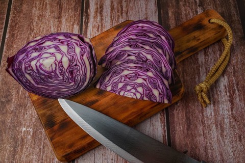 Close-up of a red cabbage or purple cabbage cut with a knife on a wooden board