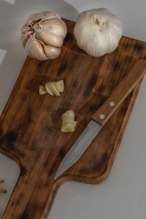 Whole and peeled garlic on wooden board and white background