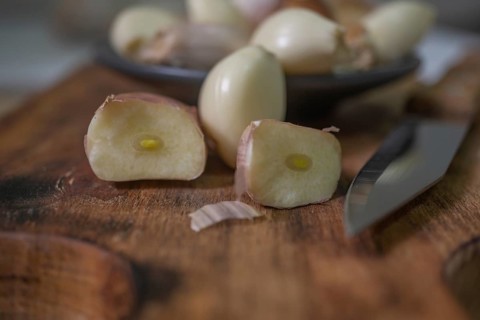 Whole and peeled garlic on wooden board and white background