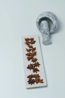 Close-up of star anise illicium verum in a white dish with a marble mortar isolated on white