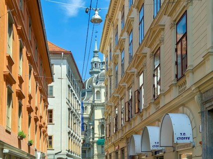 Lively old town alleyway with historic buildings and church tower in the background Landhaus Graz